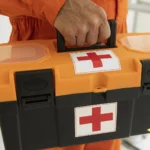 Close-up da mão de um homem carregando uma maleta de kit de emergência com itens essenciais.